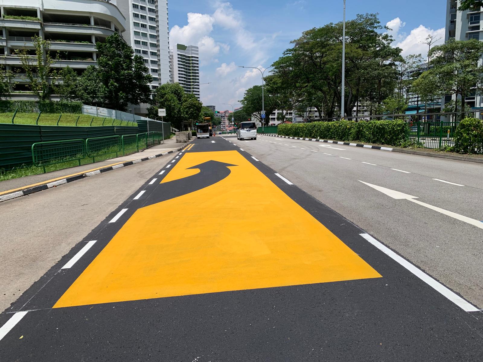 Yellow directional arrow road marking on a multi-lane road with a bus by EMK Construction